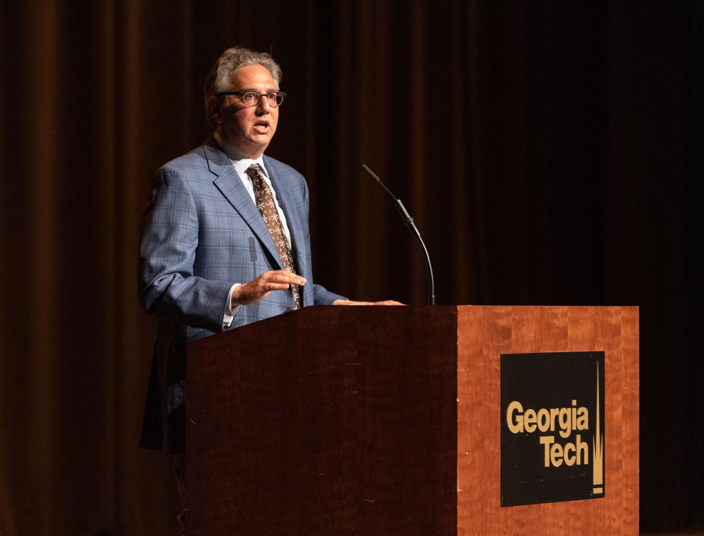 Adam Stulberg stands at a lectern with the Georgia Tech logo on it to address an audience.